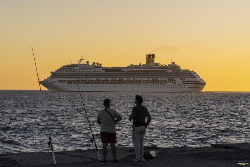 Fishers watch a cruise ship exit the port of Montevideo, March 2024