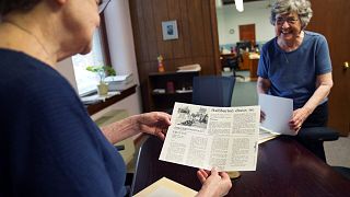 Benedictine sisters, Rose Marie Stallbaumer, left, and Barbara McCracken, right, look through corporate resolution archives and newspaper clippings.