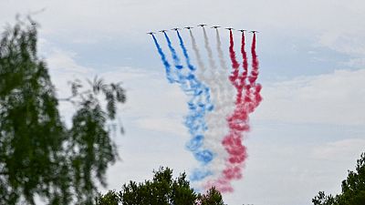 Alphajet aircrafts from Patrouille de France release smoke trails in the colors of the French flag during a ceremony marking the 80th anniversary of the Allied landings.