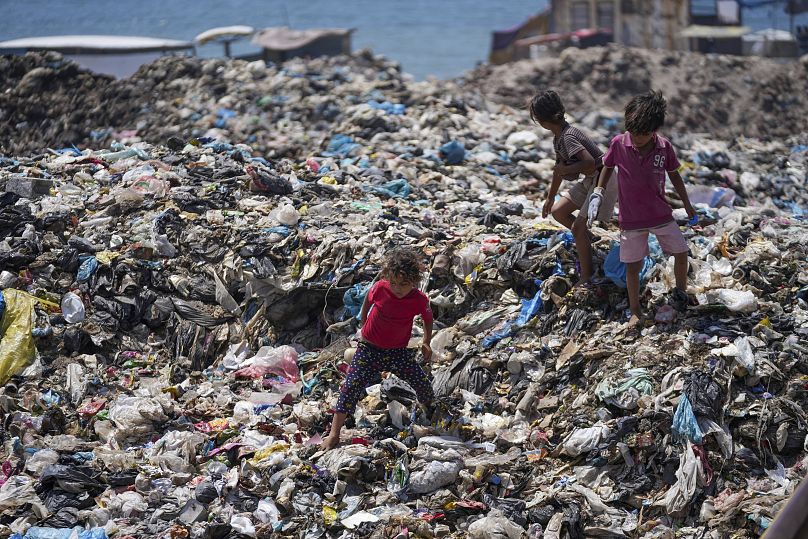 Crianças palestinianas separam o lixo num aterro sanitário no campo de refugiados de Nuseirat, 20 de junho de 2024