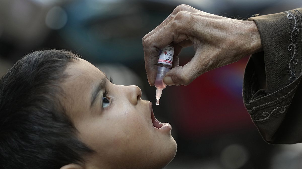 Una mujer administra la vacuna de la polio a un niño en Pakistán (Foto de archivo)