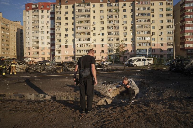 Young men look on shrapnel after Russian airstrike on residential neighbourhood in Sumy, Ukraine, on Saturday, Aug. 17, 2024.