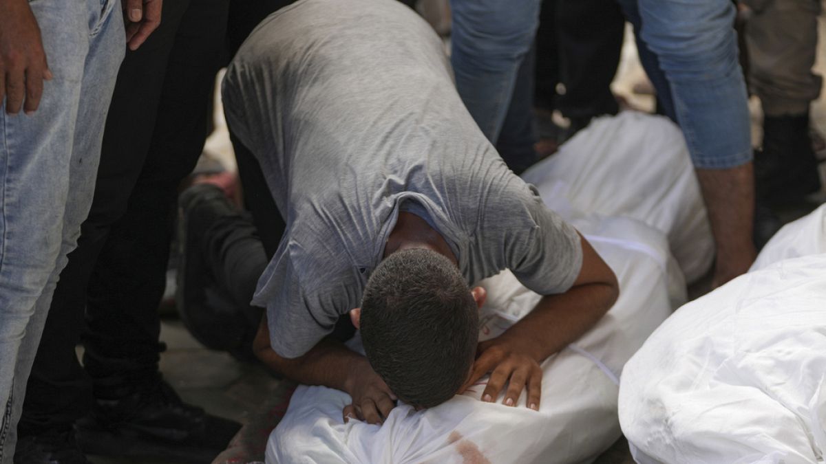 Un Palestinien pleure sur un corps lors des funérailles de plus de 15 personnes, tuées lors d'une frappe israélienne, dans la bande de Gaza, le samedi 17 août 2024. 