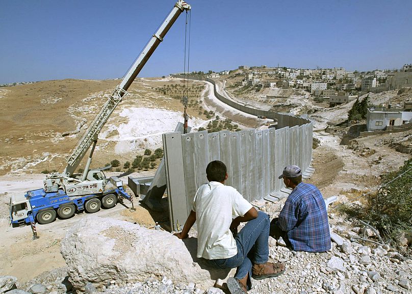 فلسطینیان در حال نظاره کردن ساخت دیوار حائل توسط اسرائیلی‌ها در سال ۲۰۰۴