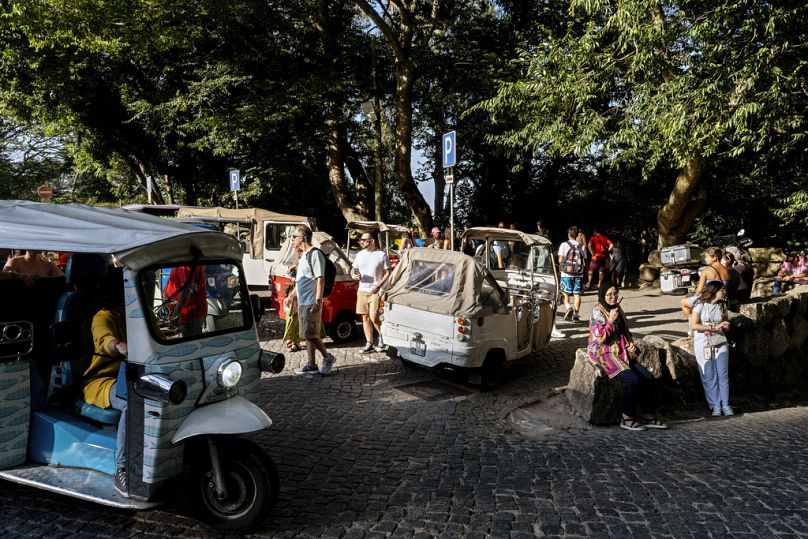 Tuk-tuks drop off and pick up tourists at the gate of the 19th century Pena Palace in Sintra, Portugal, Friday, August 9, 2024.