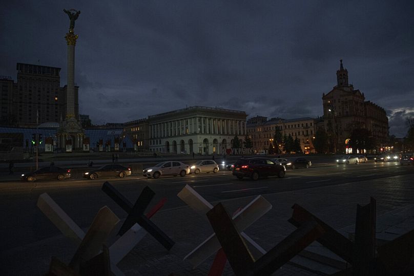 Cars pass in Independence Square at twilight in Kyiv, Ukraine, Monday, Oct. 31, 2022. 