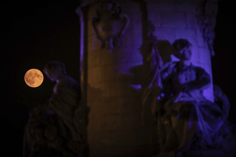 The supermoon appears behind the statue on Place de la République, Monday, Aug. 19, 2024, in Paris.