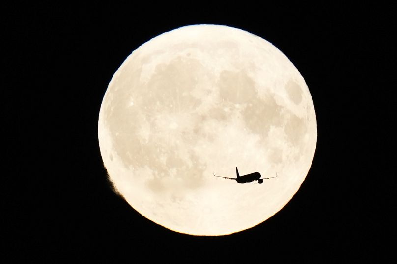 Un avion passe devant la super lune au-dessus de Copenhague, le lundi 19 août 2024.