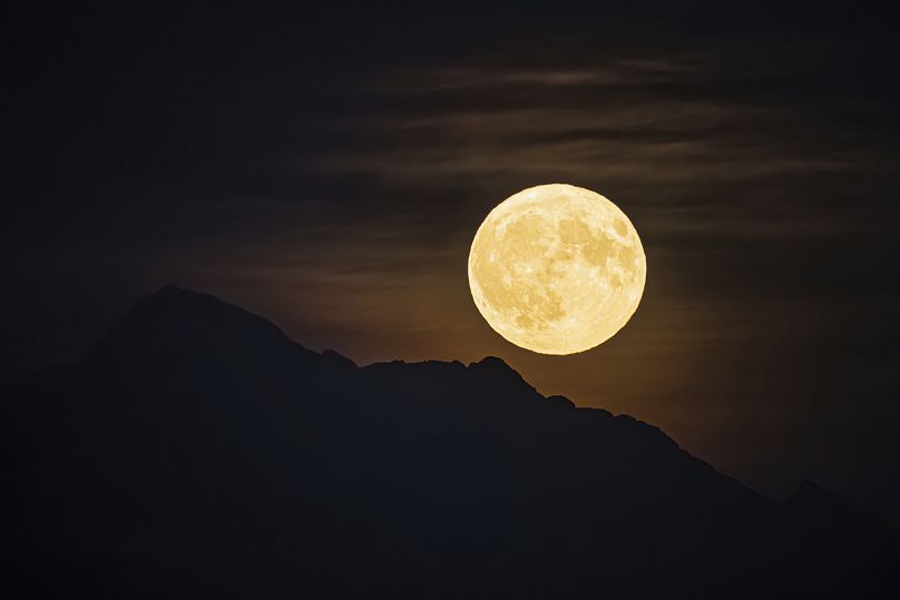 Une soi-disant super lune bleue s'élève au-dessus de la montagne « Dent d'Oche » vue depuis Allaman, en Suisse, le lundi 19 août 2024.