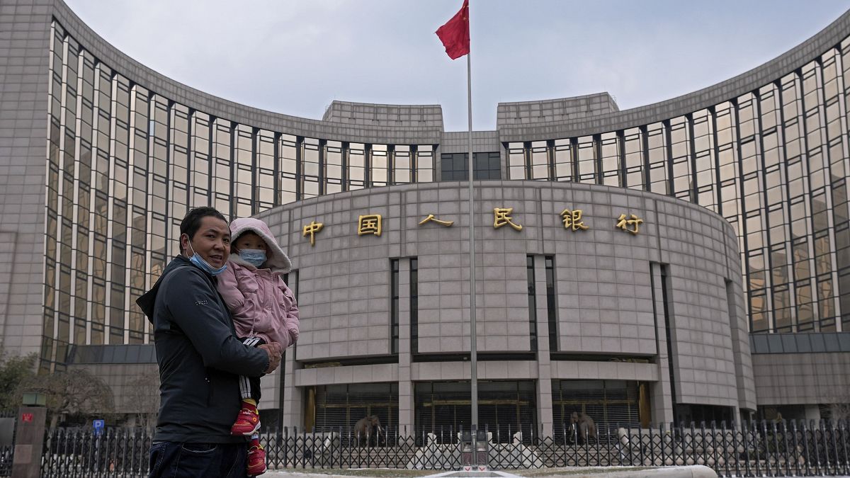 A man carries a child in front of China's central bank in Beijing