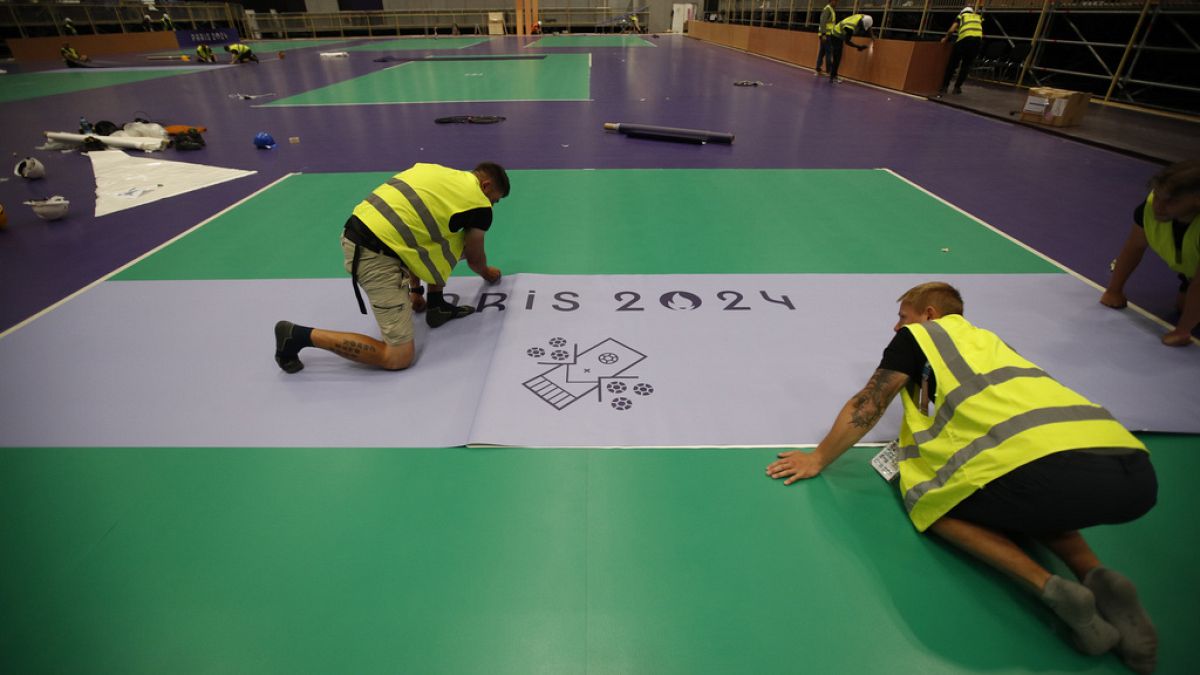 Des ouvriers préparent le terrain de boccia lors d'une visite de l'Arena Paris Sud en vue des Jeux Paralympiques, lundi 19 août 2024 à Paris. 