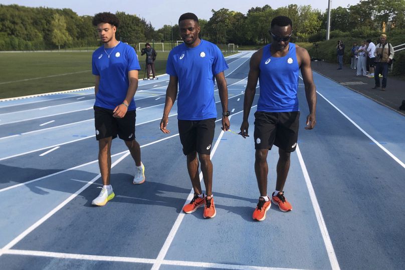 Donard Ndim Nyamjua, center, guide for sprinter Guillaume Junior Atangana, right, a member of the Refugee Paralympic Team, arrive for a training session at the training camp. 