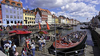 Turistas embarcam num ferry turístico na zona histórica do porto de Nyhavn, em Copenhaga, Dinamarca, no domingo, 28 de julho de 2024.