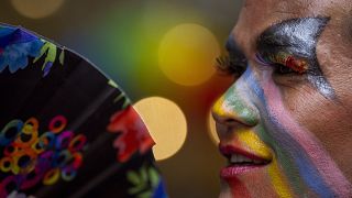 A participant has colors painted on face as LGBTQ+ people and their supporters rally during the annual pride parade.