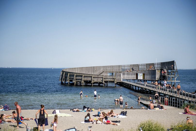 People bathe in the sea and sit on the beach at the Kastrup seaside resort in Copenhagen, Denmark, Friday June 1, 2018. 