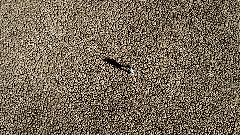 A man walks on the cracked ground of the Sau reservoir in Vilanova de Sau, about 100 km north of Barcelona, Spain, on 26 Jan 2024.