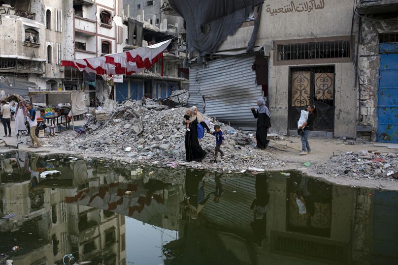 ملف - فلسطينيون نزحوا بسبب الهجوم الجوي والبري الإسرائيلي على قطاع غزة يسيرون بجوار خط مظلم من مياه الصرف الصحي تتدفق إلى شوارع مدينة خان يونس الجنوبية بقطاع غزة، الخميس 4 يول