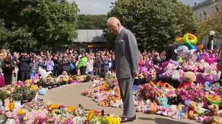 In honor of the victims, King Charles III bends over flowers.