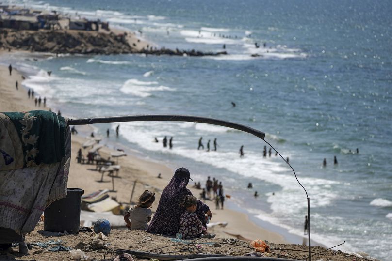 نازحون فلسطينيون يجلسون بجوار خيمتهم أثناء تخييمهم على الشاطئ، غرب دير البلح، قطاع غزة، الثلاثاء، 20 أغسطس/آب 2024