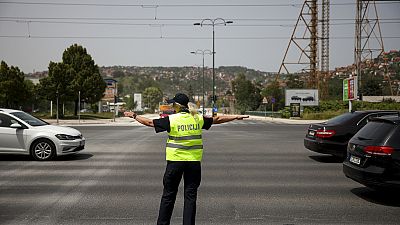 A police officer gestures towards cars as she tries to control traffic during a power outage in Sarajevo, Bosnia, Friday, June 21, 2024.