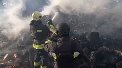 Pompiers tentant d'éteindre les cendres d'une station service suite à une frappe russe  