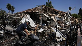 Un uomo vicino a una casa distrutta dopo il lancio di razzi a Katzrin, nelle Alture del Golan annesse a Israele, 21 agosto 2024