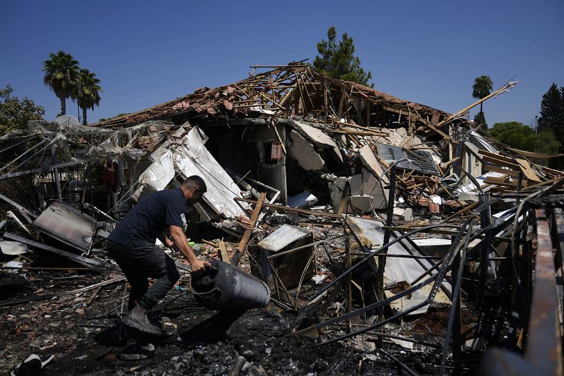 Un homme travaille à côté d'une maison détruite par des roquettes à Katzrin, sur le plateau du Golan annexé par Israël, le mercredi 21 août 2024.