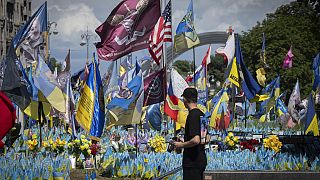 A passer-by looks at a makeshift memorial for fallen Ukrainian soldiers on Independence Square in Kyiv, Ukraine, Tuesday, July 23, 2024. 