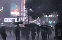 People rushing with umbrellas through heavy rain near Shibuya station