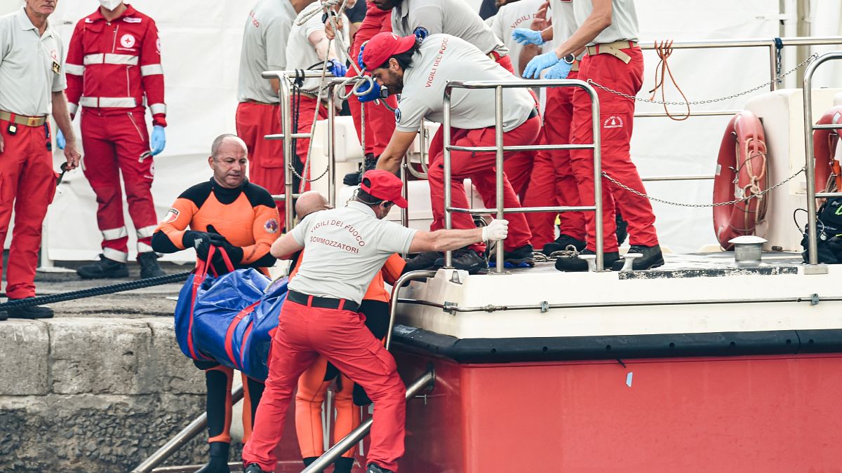 Az olasz tűzoltóság tagjai egy holttesttel a kezükben