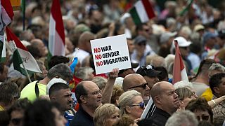 Des personnes tiennent une pancarte sur laquelle on peut lire « Pas de guerre, pas de sexe, pas de migration » lors d'une « marche pour la paix » à Budapest, 01.06.2024