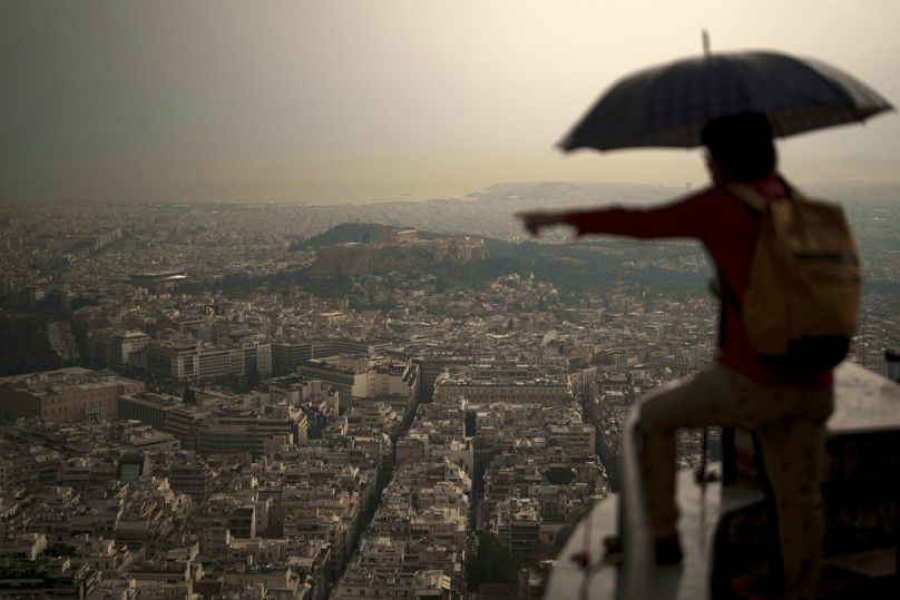 A tourist holds an umbrella during a sudden rain shower in Lycabettus Hill , Athens, Greece.