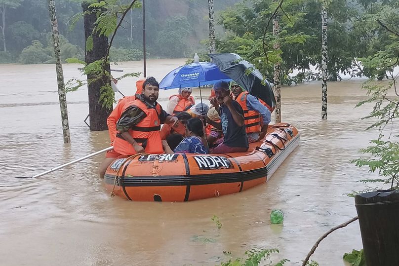 في هذه الصورة التي أتاحتها القوة الوطنية للاستجابة للكوارث (NDRF)، يقوم أفراد القوة الوطنية للاستجابة للكوارث بنقل الناس إلى بر الأمان عبر منطقة غمرتها المياه بعد هطول أمطار م