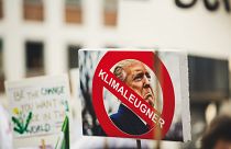 A sign with Donald Trump reading 'climate denier'. 