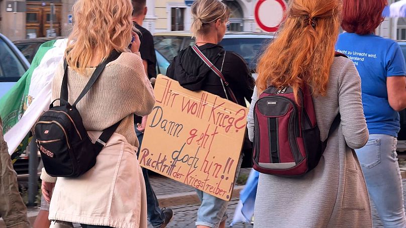 Demonstranten auf der Görlitzer Montagsdemonstration mit einem Plakat, auf dem die Regierung an der Kriegstreiberei beschuldigt wird.