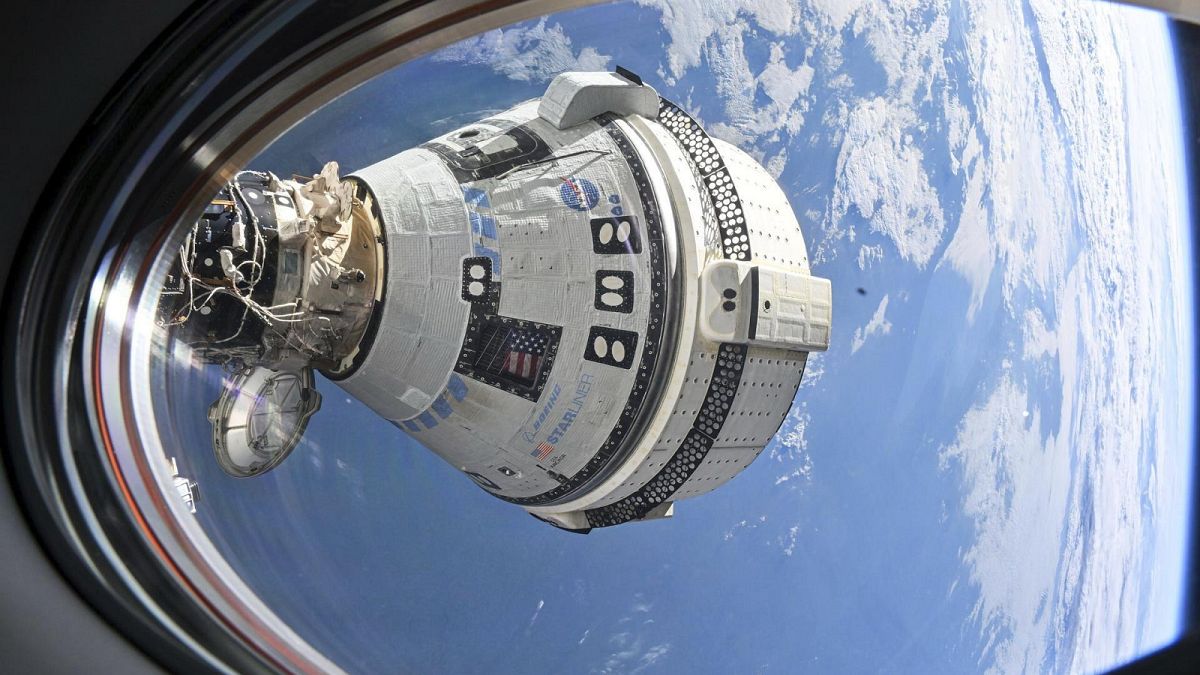 Boeing's Starliner spacecraft seen from a window on the SpaceX Dragon Endeavour spacecraft docked to the adjacent port.