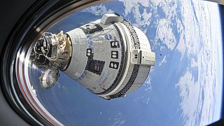 Boeing's Starliner spacecraft seen from a window on the SpaceX Dragon Endeavour spacecraft docked to the adjacent port.