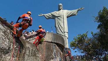 Climbers rappelling down to collect trash on slope 