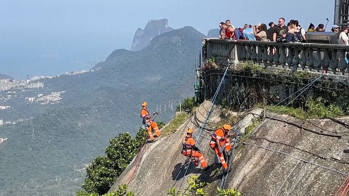 Des alpinistes descendent en rappel pour ramasser les déchets accumulés sous la statue