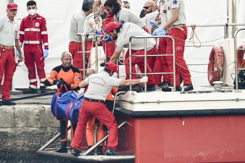 غواصو رجال الإطفاء الإيطاليون ينقلون جثة أحد ضحايا غرق سفينة إلى الشاطئ في كيس بلاستيكي، في بورتيتشيلو، صقلية، جنوب إيطاليا، الخميس، أغسطس 2018. 22, 2024.