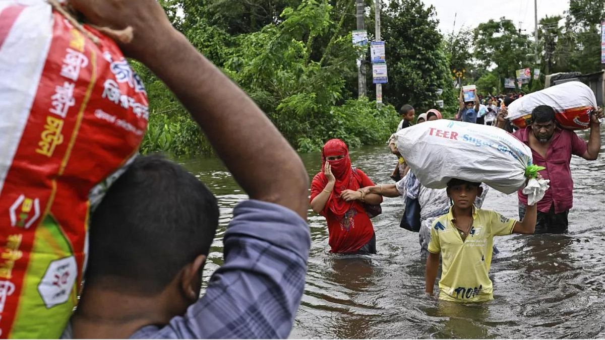 Des gens marchent vers un abri de secours avec leurs effets personnels à travers une rue inondée après de fortes pluies au sud-est du Bangladesh