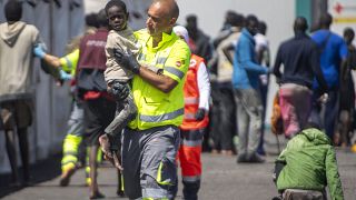 Un bambino viene assistito da un membro della squadra di emergenza dopo essere stato salvato da una barca nel porto di La Restinga, sull'isola canaria di El Hierro