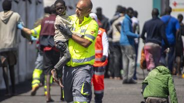 Un bambino viene assistito da un membro della squadra di emergenza dopo essere stato salvato da una barca nel porto di La Restinga, sull'isola canaria di El Hierro