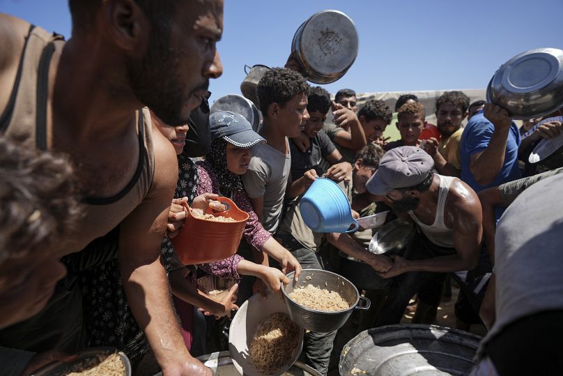 Displaced Palestinians gather for food distribution in Deir al Balah, central Gaza Strip, Friday, Aug. 23, 2024.