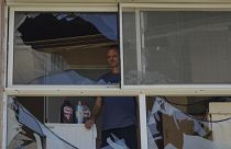 A man looks at a damaged window of a house following an attack from Lebanon, in Acre, north Israel, Sunday, Aug. 25, 2024