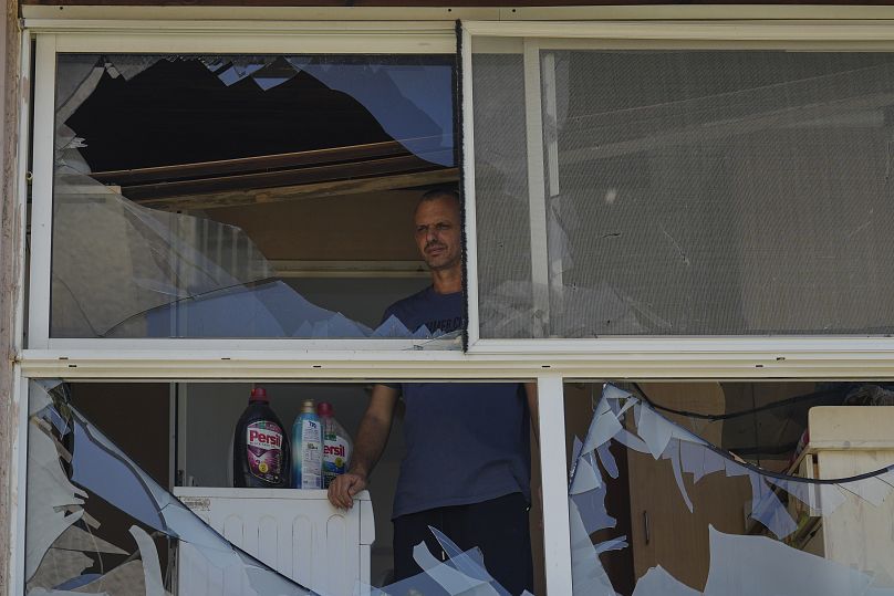 A man looks at a damaged window of a house following an attack from Lebanon, in Acre, north Israel, Sunday, Aug. 25, 2024