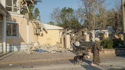 A woman walks with her dog in front of the Sapphire hotel which was destroyed by a Russian rocket attack in Kramatorsk, 25 August 2024