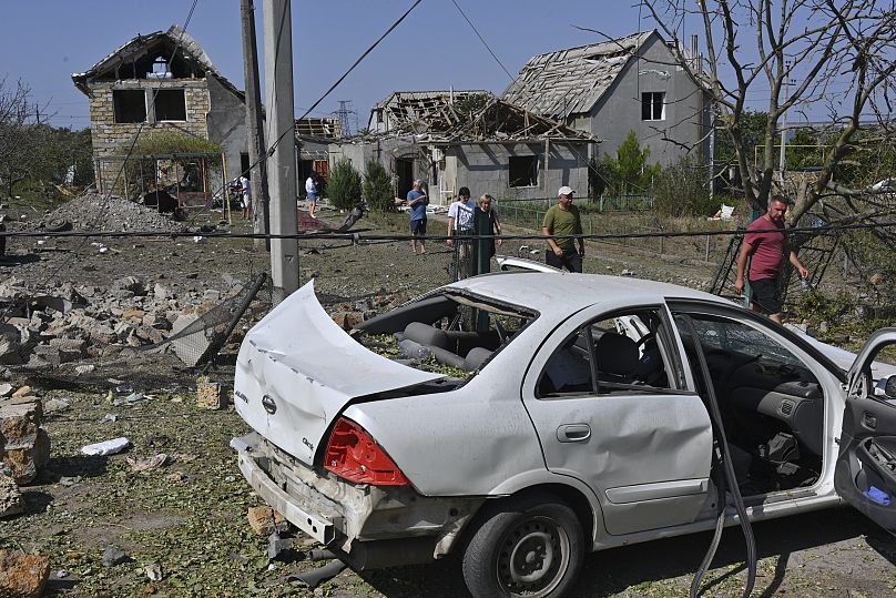 Des personnes marchent devant leurs maisons endommagées après une attaque de roquettes russes dans le village d'Usatove près d'Odesa, en Ukraine, le lundi 26 août 2024. 