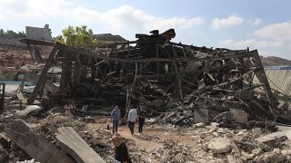 People walk at an industrial area destroyed by an Israeli airstrike, in Wadi al-Kfour, Nabatieh province, south Lebanon. 17 August 2024.