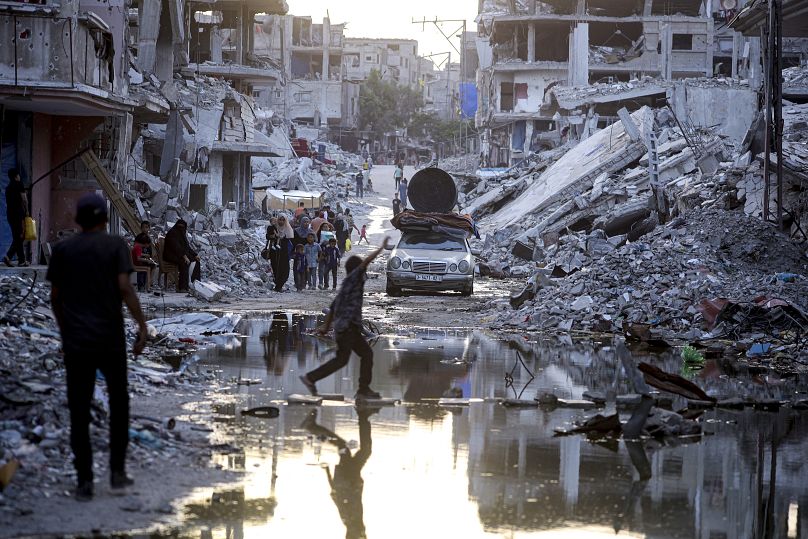 Palestinians displaced by the Israeli offensive in Gaza walk past sewage flowing into the streets of Khan Younis, July 4, 2024